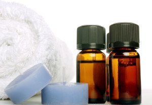 assortment of essential oils, lavender candles and towel.